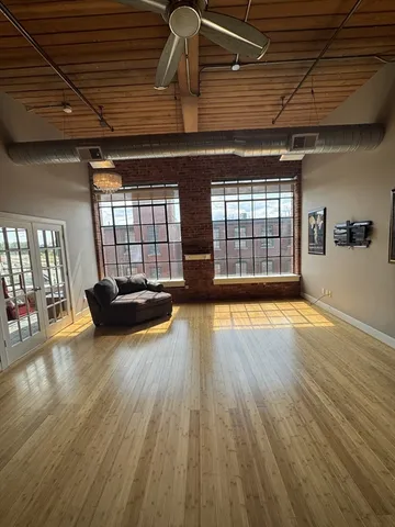 an empty room with wooden floor and windows