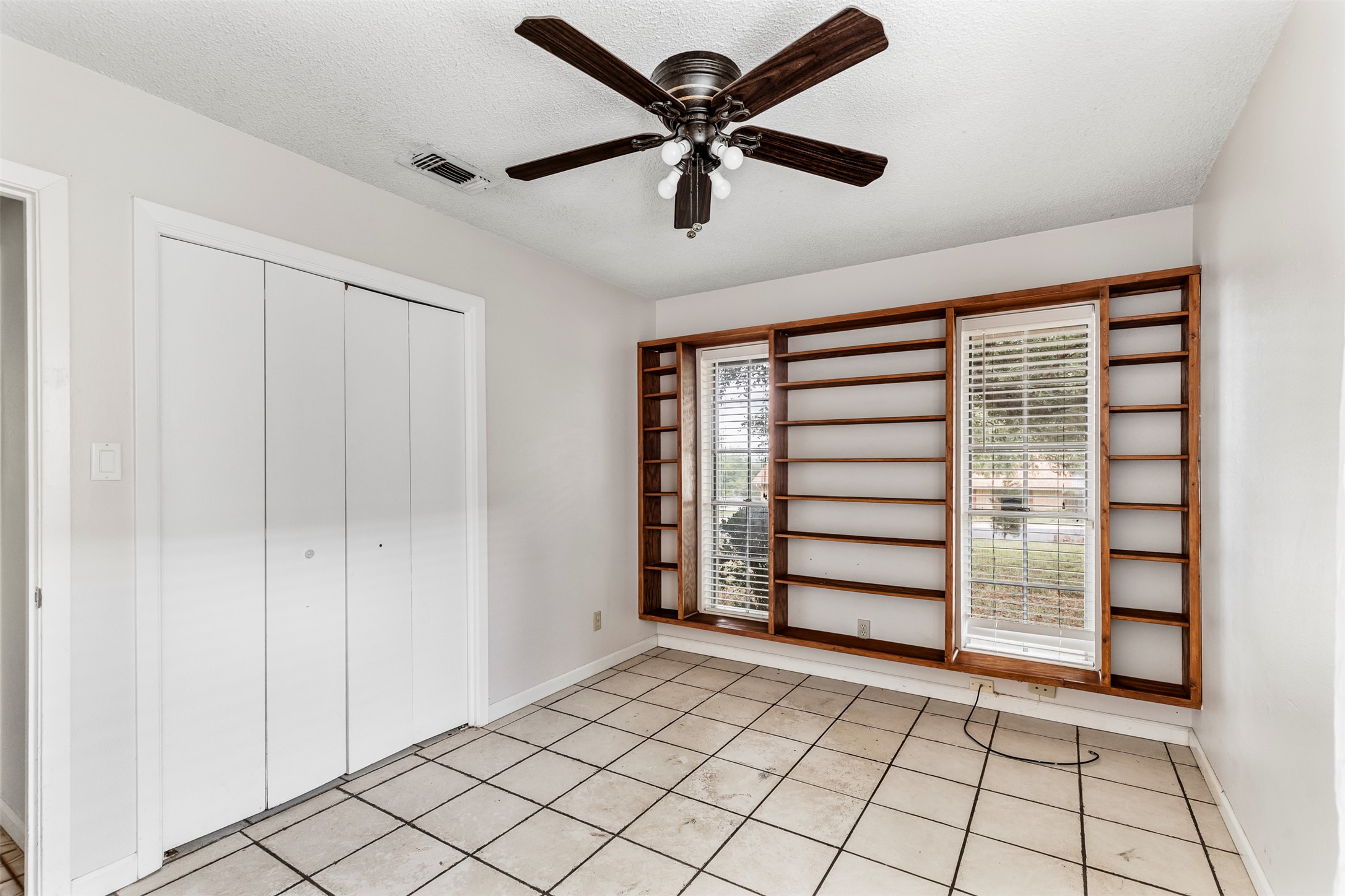 7506 Glenhill Road Austin, TX 78752 - Photo 11 of 24 Built-in shelving surrounds dual windows, offering both storage and natural light to this versatile room.