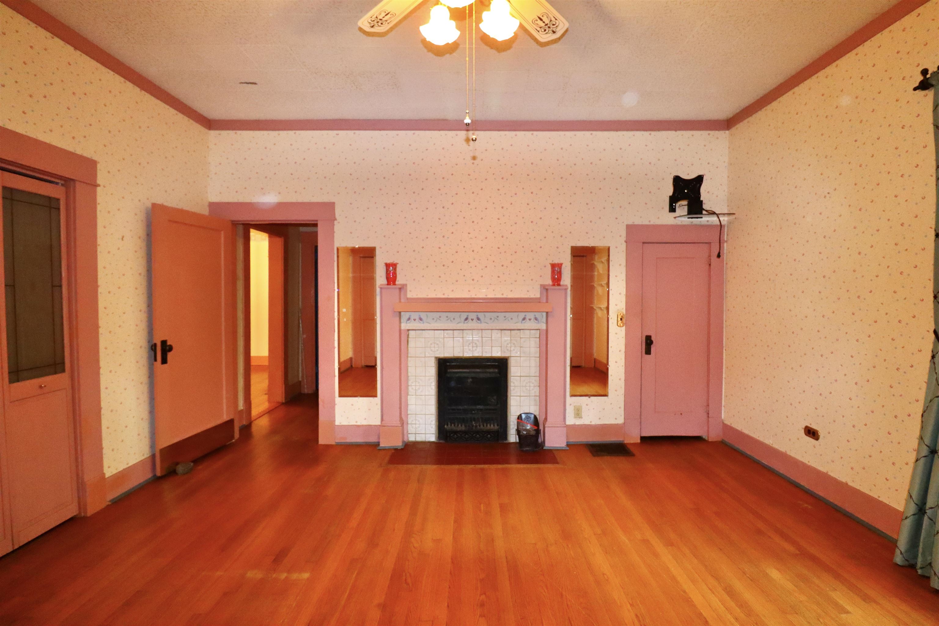 317 Purdy Road Selmer, TN 38375 - Photo 30 of 38 Unfurnished living room featuring crown molding, ceiling fan, a tiled fireplace, and hardwood / wood-style flooring