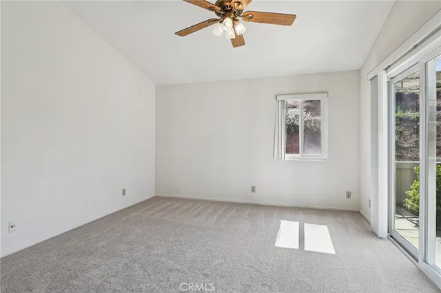 an empty room with windows and chandelier fan