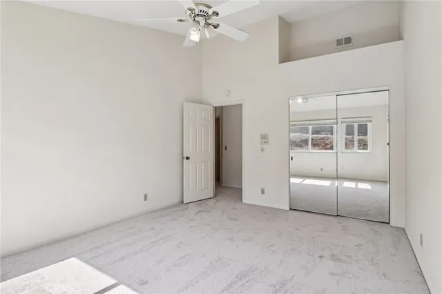 an empty room with a chandelier fan and closet area