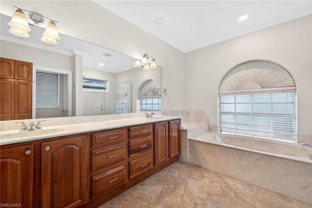 2229 Goshawk Court Naples, FL 34105 - Photo 11 of 27 a spacious bathroom with a granite countertop double vanity sink a mirror and a bathtub with shower