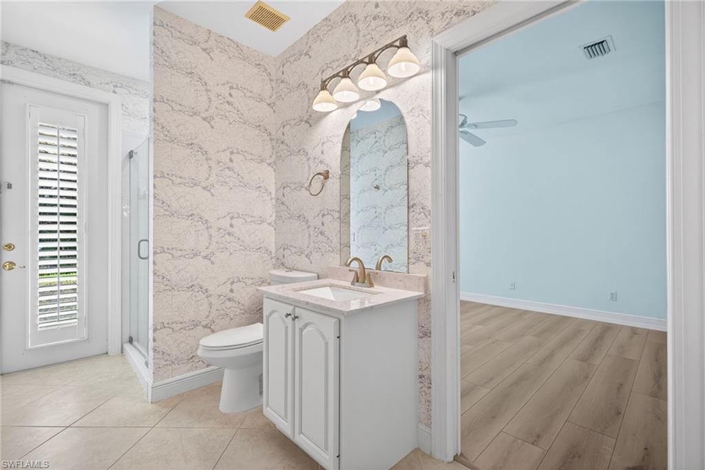 2229 Goshawk Court Naples, FL 34105 - Photo 15 of 27 a bathroom with a granite countertop sink a toilet and a mirror