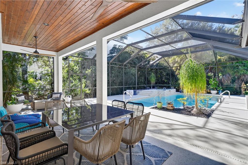 2229 Goshawk Court Naples, FL 34105 - Photo 19 of 27 a view of patio with table and chairs potted plants and large tree