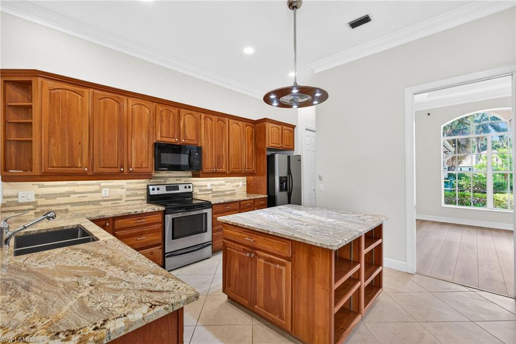 2229 Goshawk Court Naples, FL 34105 - Photo 6 of 27 a kitchen with a stove center island and cabinets