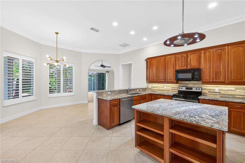 2229 Goshawk Court Naples, FL 34105 - Photo 7 of 27 a kitchen with kitchen island granite countertop wooden cabinets a stove a sink and a oven