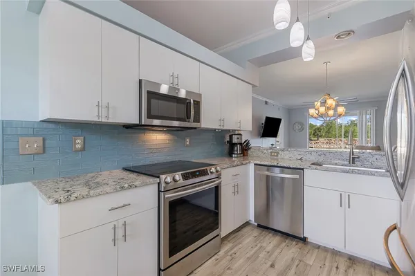 a kitchen with stainless steel appliances granite countertop a refrigerator a sink and white cabinets