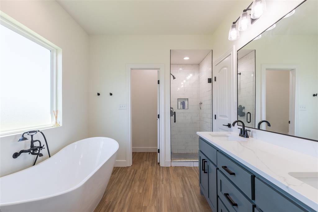 118 Corbyn Circle Tuscola, TX 79562 - Photo 16 of 36 a bathroom with a double vanity sink a mirror and a bathtub