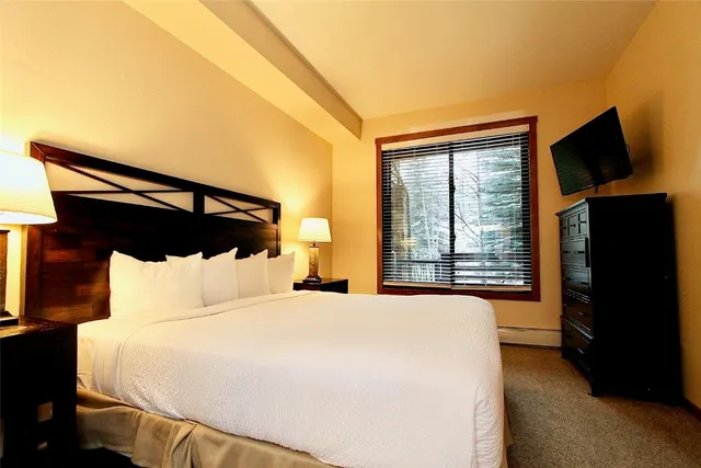 a bedroom with a bed and a flat tv screen on a dresser