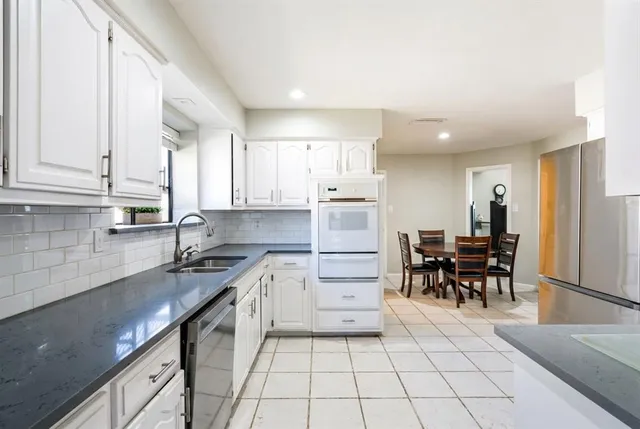 a kitchen with granite countertop a sink cabinets and stainless steel appliances