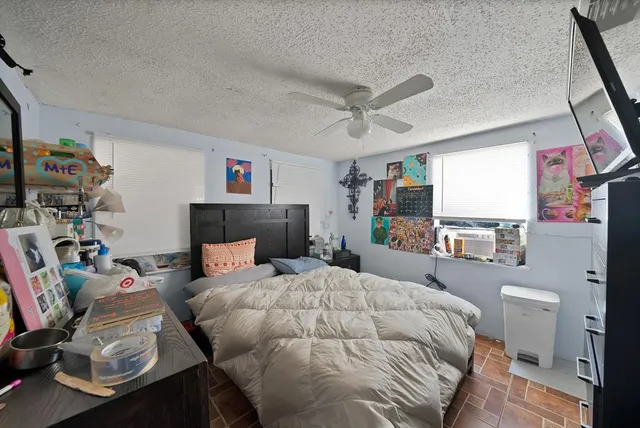 a bedroom with a bed a couch and a flat tv screen on the dresser