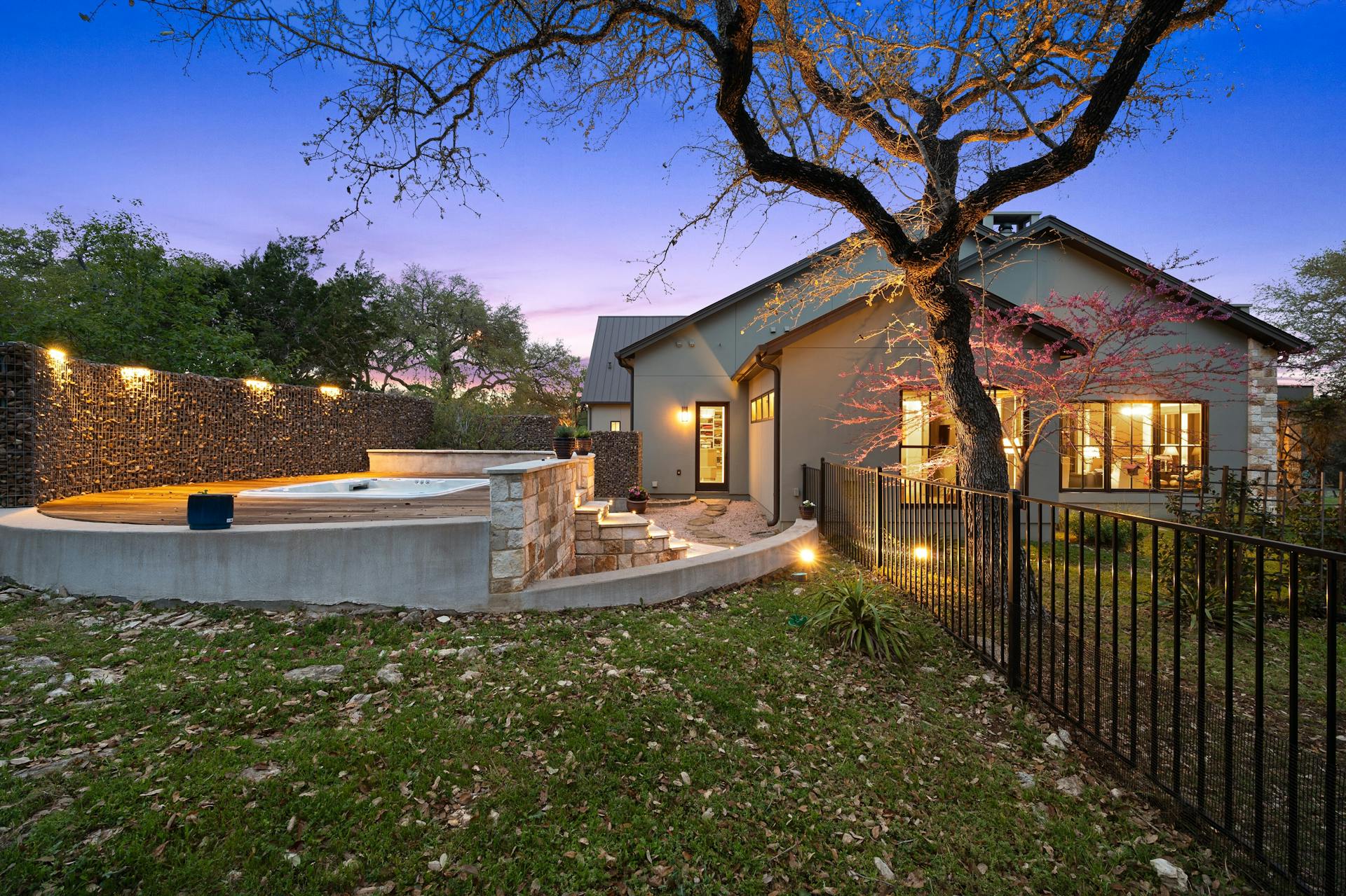 1330 Ranchers Club Lane Driftwood, TX 78619 - Photo 36 of 40 Back of property at dusk with a fenced backyard, a patio area, an outdoor hot tub, and stucco siding
