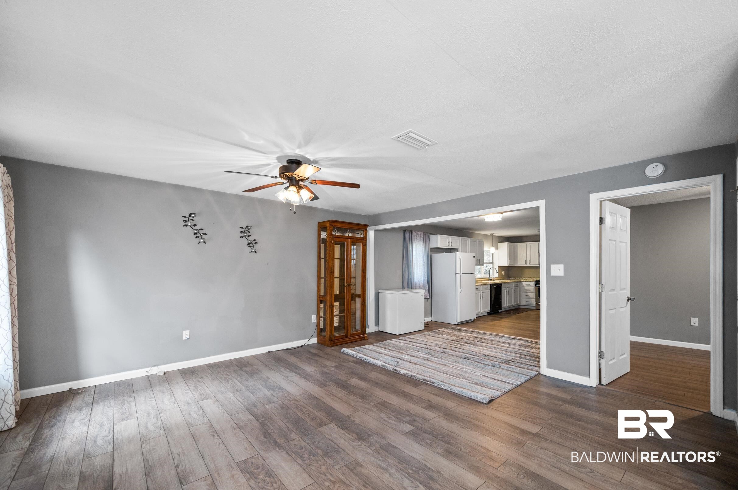 906 North Cedar Street Foley, AL 36535 - Photo 5 of 24 Unfurnished living room featuring dark wood-type flooring and ceiling fan