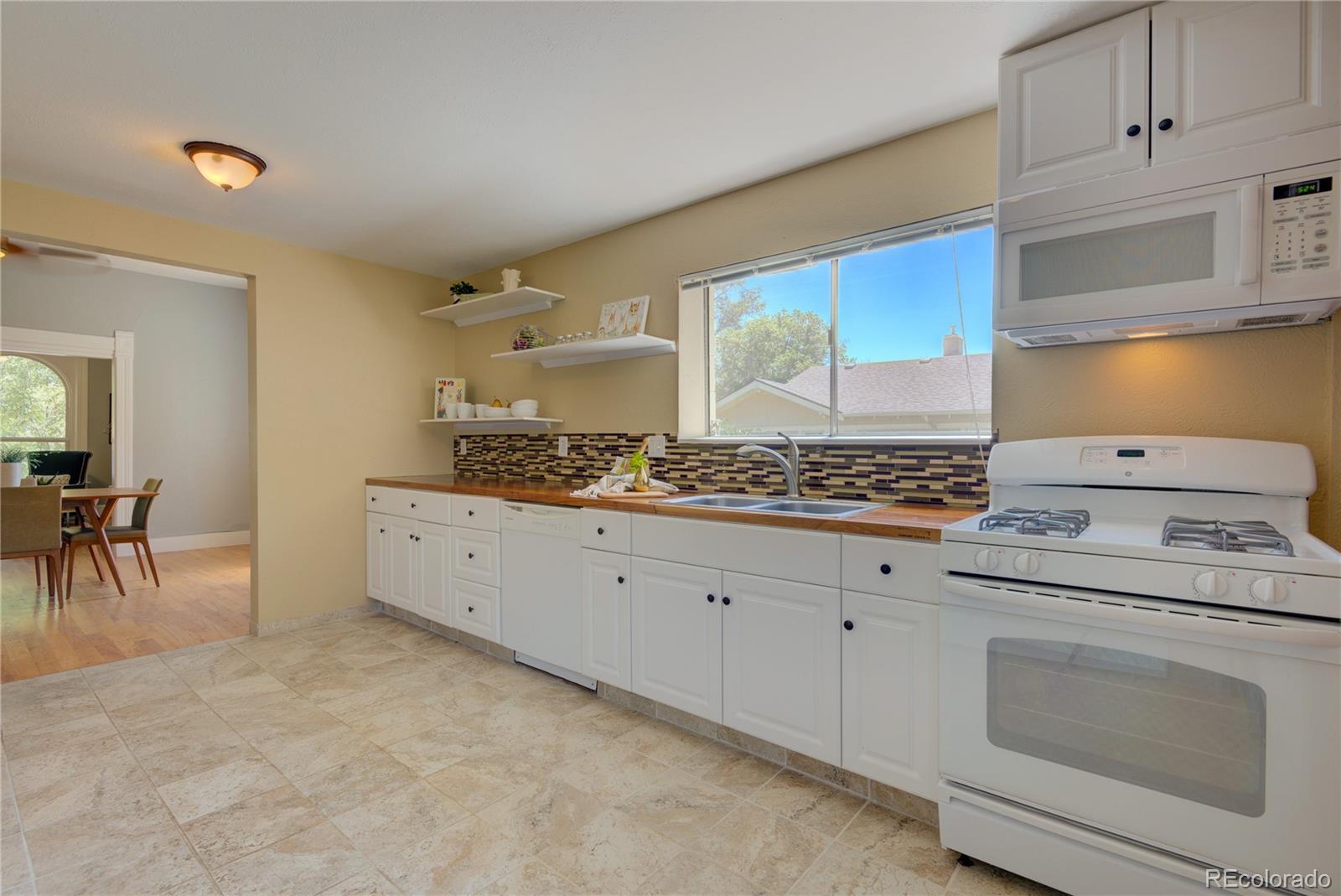 2537 Ames Street Edgewater, CO 80214 - Photo 15 of 38 a kitchen with granite countertop white cabinets and white appliances