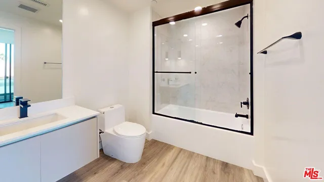 a bathroom with a granite countertop sink a toilet and shower