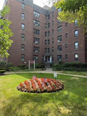 a front view of a building with a yard and plants