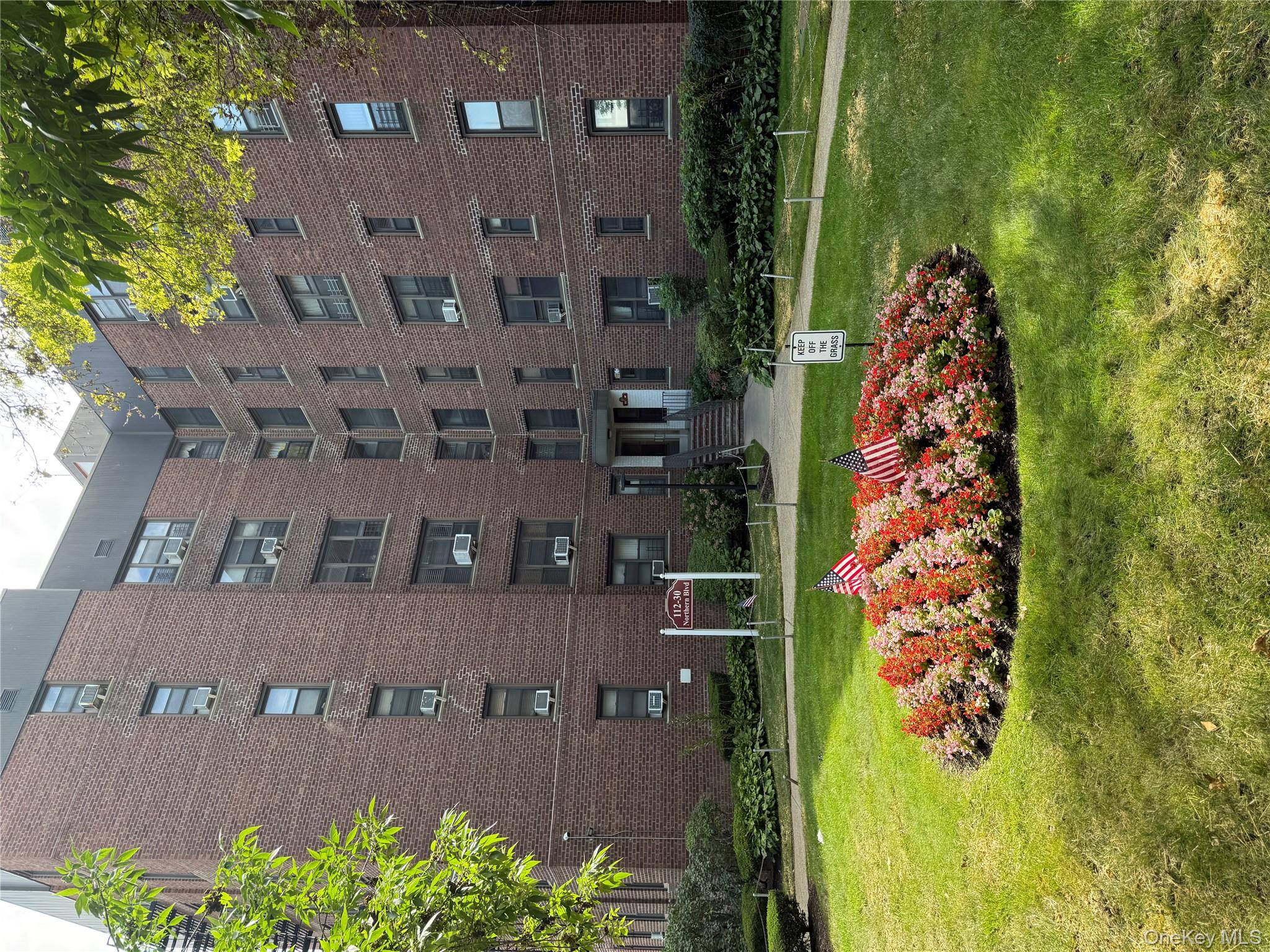 a front view of a building with a yard and plants