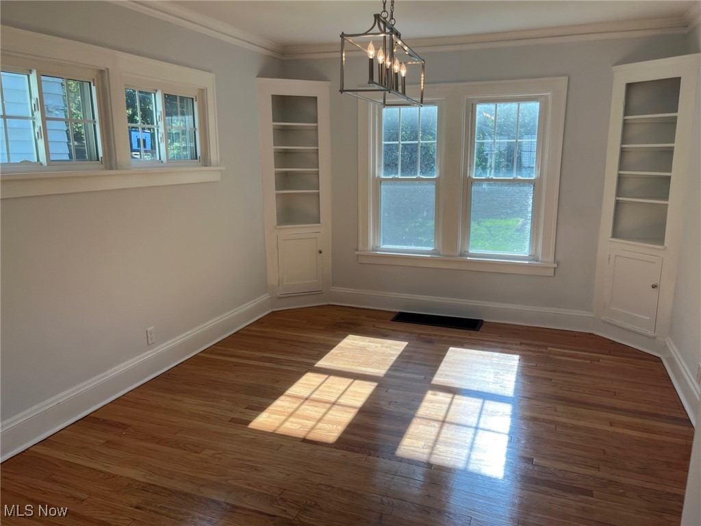 1148 Sylvania Road Cleveland Heights, OH 44121 - Photo 7 of 30 Unfurnished dining area with ornamental molding, dark wood-type flooring, a chandelier, and built in features