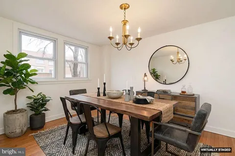a dining room with wooden floor a chandelier a wooden table and chairs