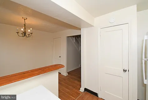 a view of a hallway with wooden floor and chandelier