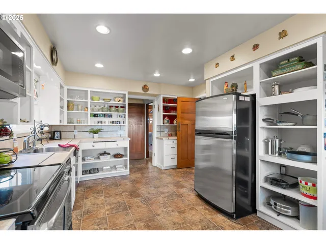 a kitchen with stainless steel appliances kitchen island granite countertop a refrigerator a stove and a sink with wooden cabinets