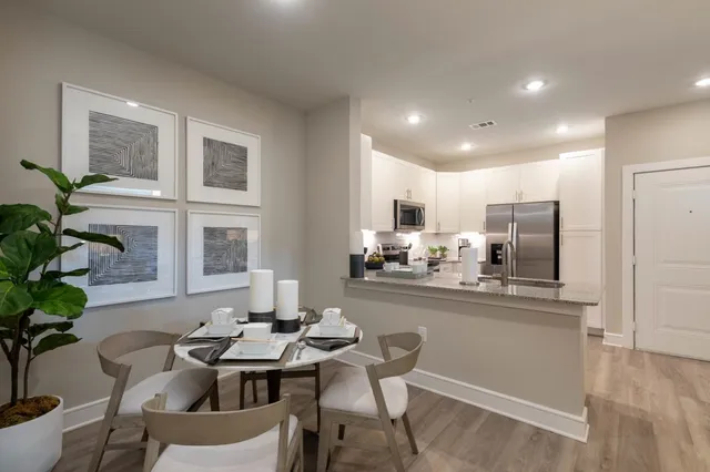 a kitchen with stainless steel appliances kitchen island granite countertop a refrigerator oven a sink dishwasher and white cabinets with wooden floor