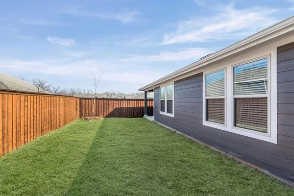 a view of a backyard with grass and wooden fence
