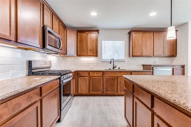 a kitchen with stainless steel appliances granite countertop wooden cabinets a stove top oven a sink and dishwasher