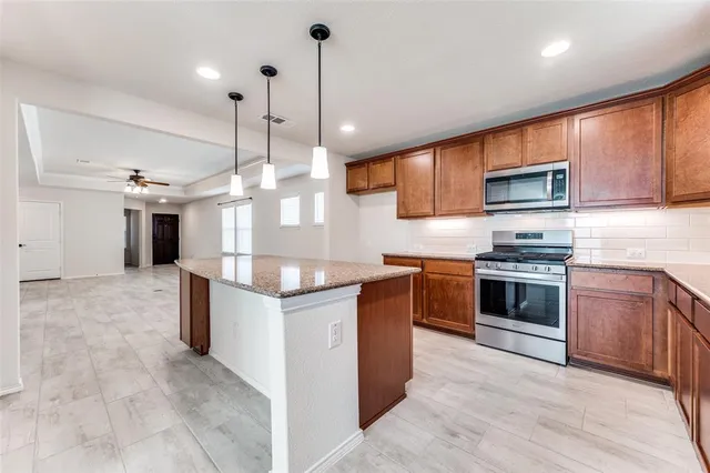 a kitchen with stainless steel appliances granite countertop a sink a counter space and wooden floor