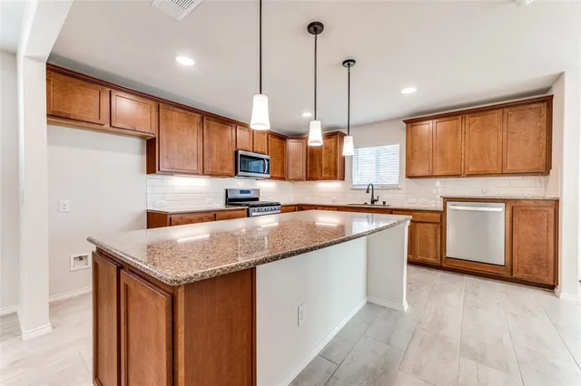 a kitchen with stainless steel appliances granite countertop a stove a sink and a microwave