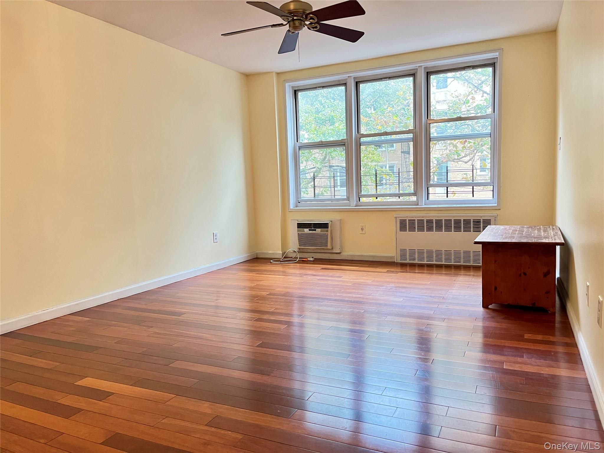 142-15 Franklin Avenue, Unit 3F Queens, NY 11355 - Photo 3 of 15 Unfurnished room featuring radiator heating unit, hardwood / wood-style floors, a ceiling fan, and a wall mounted AC