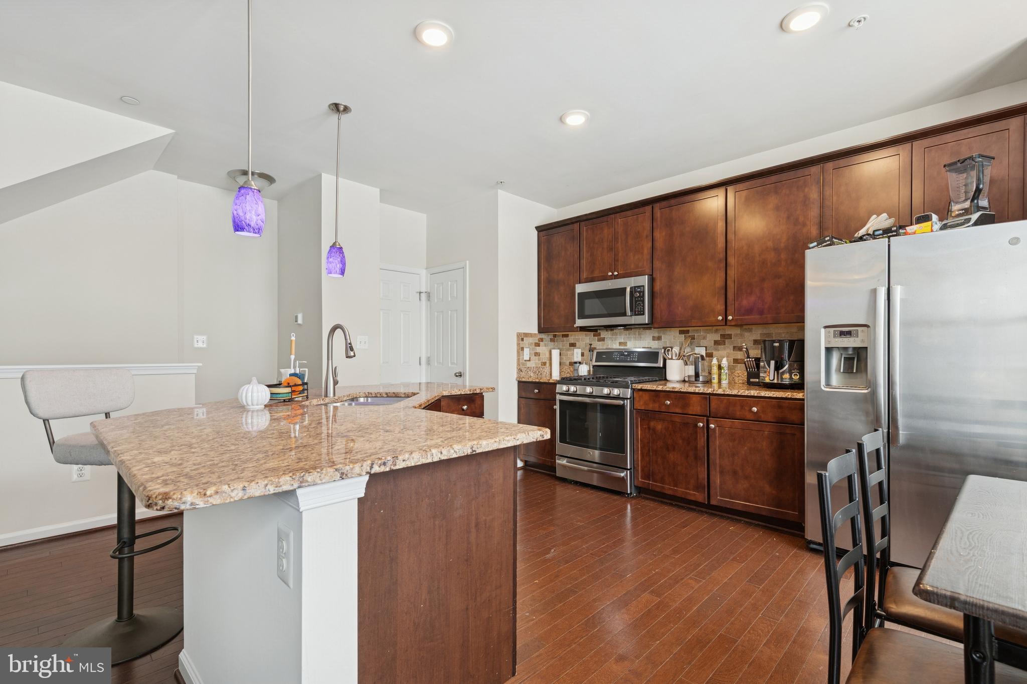 5857 Bella Marie Way, Unit F Frederick, MD 21703 - Photo 7 of 45 a kitchen with granite countertop kitchen island stainless steel appliances a refrigerator sink stove microwave and cabinets