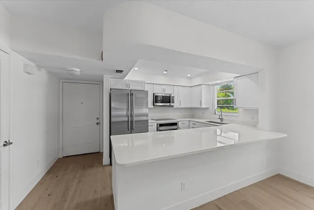 a large white kitchen with wooden floors and stainless steel appliances