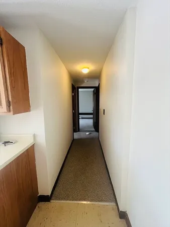 a view of a hallway with wooden floor and a bathroom