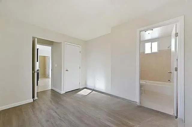an empty room with wooden floor & closet area