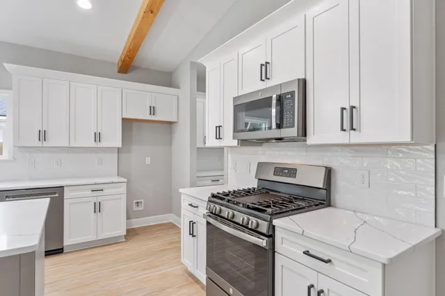 a kitchen with cabinets stainless steel appliances and wooden floor