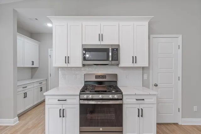 a kitchen with stainless steel appliances granite countertop white cabinets and a stove a oven with white countertops