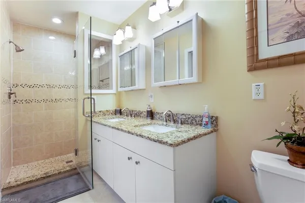 a bathroom with a granite countertop sink a toilet a mirror and shower