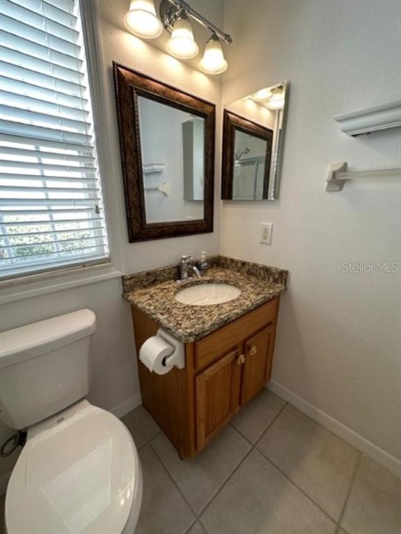 1005 Wiregrass Street Celebration, FL 34747 - Photo 23 of 31 a bathroom with a granite countertop toilet sink and mirror