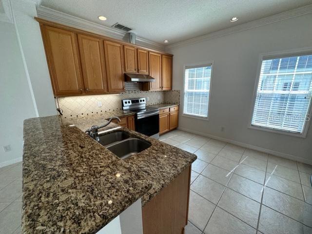 1005 Wiregrass Street Celebration, FL 34747 - Photo 7 of 31 a kitchen with stainless steel appliances kitchen island granite countertop a stove a sink and a granite counter tops