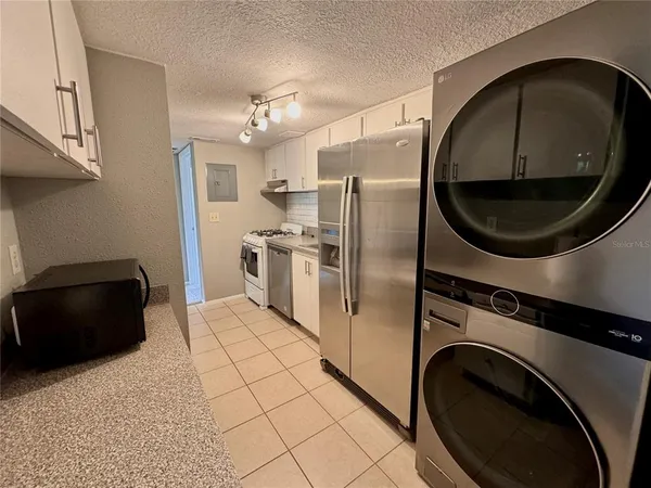 a kitchen with stainless steel appliances granite countertop a refrigerator a stove and a sink