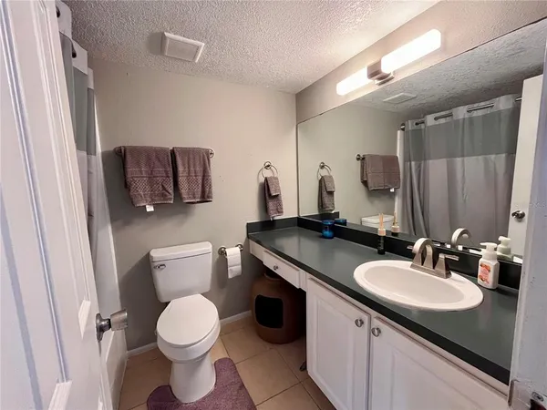 a bathroom with a granite countertop sink toilet and mirror
