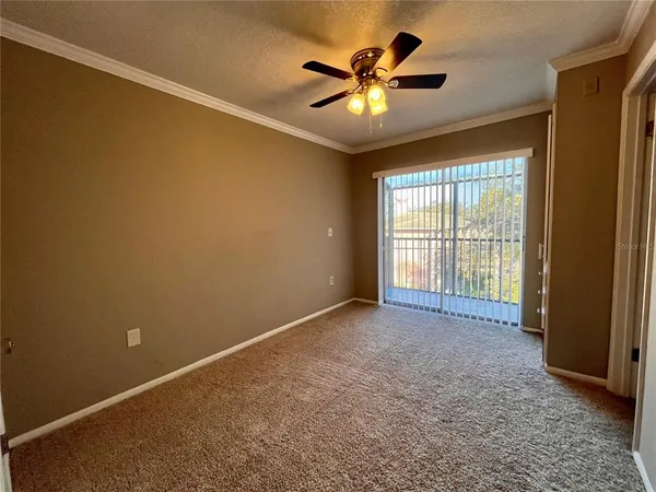 an empty room with chandelier fan and windows