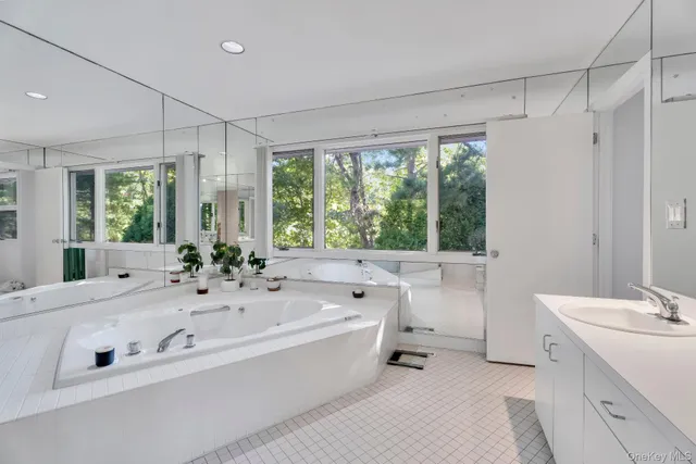 a spacious bathroom with a double vanity sink a large mirror and a bathtub next to a window