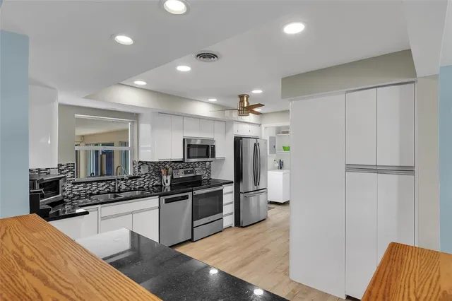 a large kitchen with stainless steel appliances kitchen island granite countertop a refrigerator and a sink