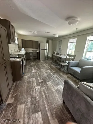 a large living room with stainless steel appliances granite countertop furniture wooden floor and a window