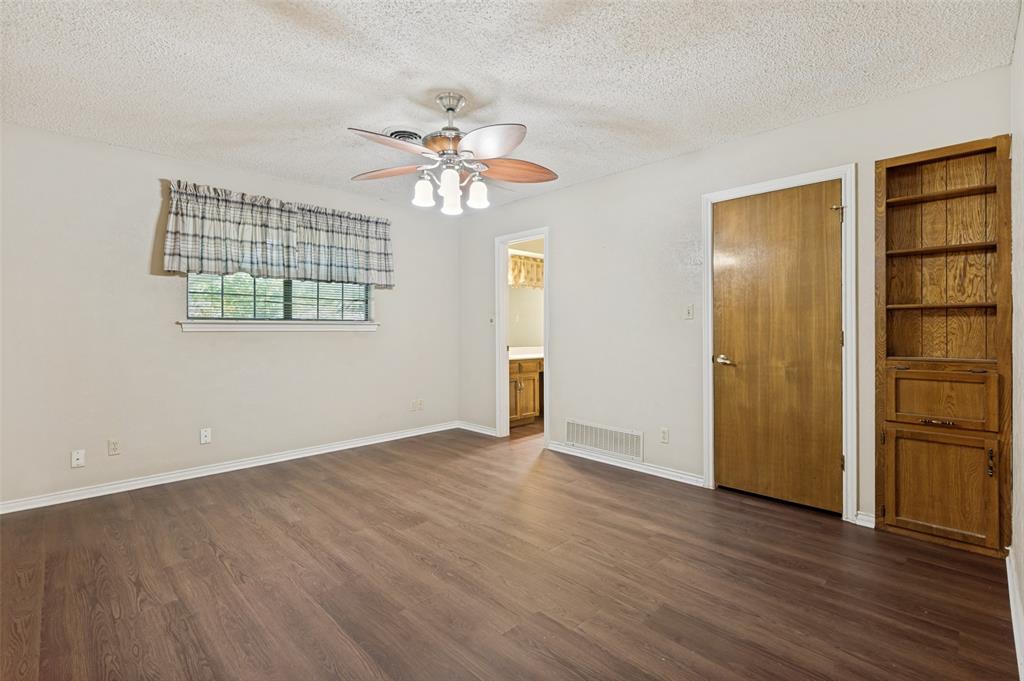 508 South Pedigo Street Pilot Point, TX 76258 - Photo 14 of 26 Spacious bedroom featuring wood-finish flooring, light-toned walls, and a ceiling fan with integrated lighting