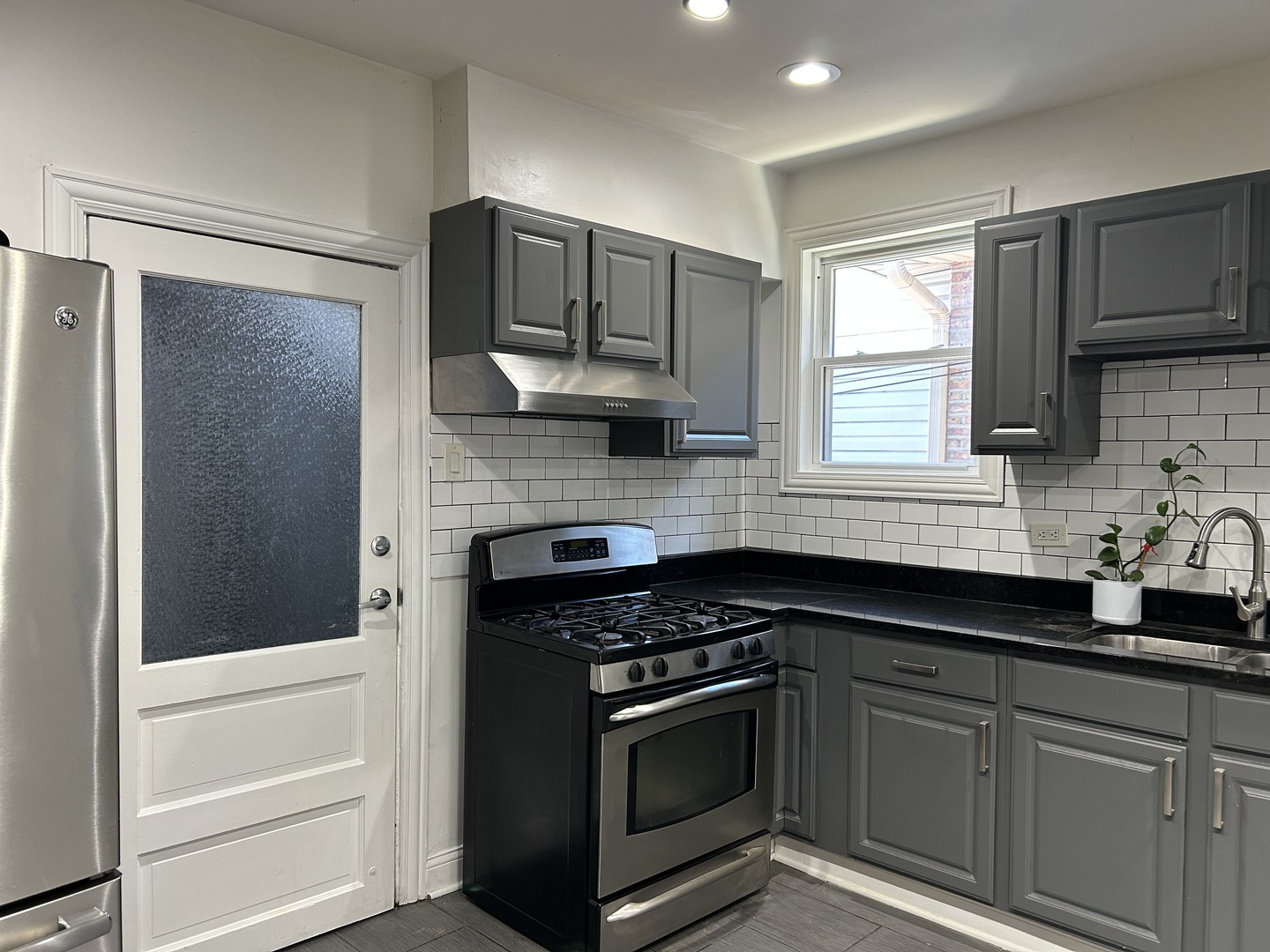 4858 West Concord Place, Unit 1 Chicago, IL 60639 - Photo 5 of 14 a kitchen with stainless steel appliances granite countertop white cabinets and window