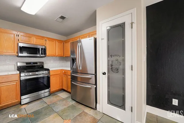a kitchen with stainless steel appliances granite countertop a refrigerator and a stove top oven