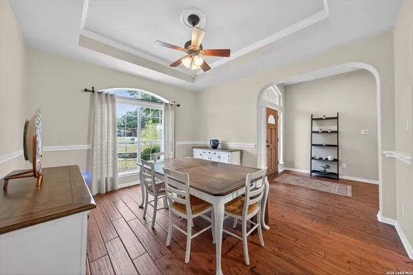 a dining room with wooden floor a chandelier fan a wooden table and chairs